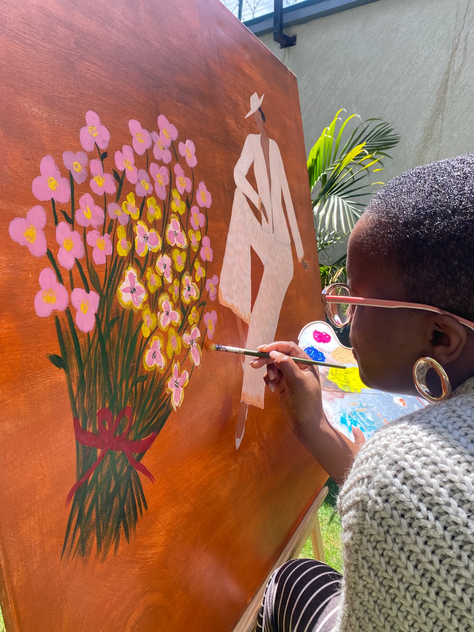 A closer view of Nelly painting pink flowers onto a canvas